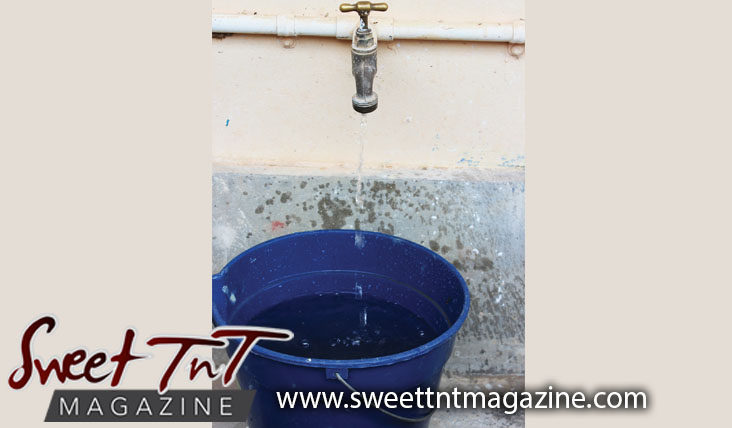Dripping pipe filling blue bucket during Dry Season, drought, lack of water, water conservation, shortage in Sweet T&T, Sweet TnT Magazine, Trinidad and Tobago, Trini, vacation, travel