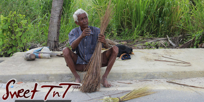 Elderly Cocoyea broom man in Aranguez on side of road barefooted, white hair, striped shirt, brown short pants, bony legs, in Sweet T&T, Sweet TnT Magazine, Trinidad and Tobago, Trini, vacation, travel
